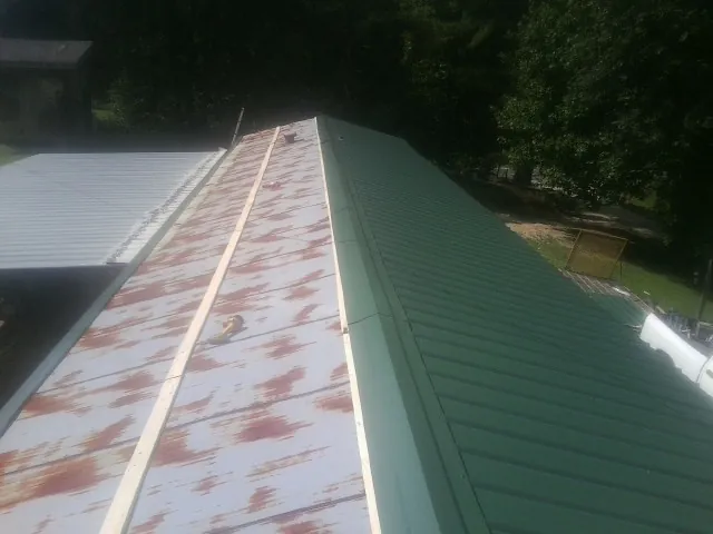 Old rusted panels beside newly installed green metal roofing — Wind Damage Roof Repair by Roofing Brothers in New Buffalo