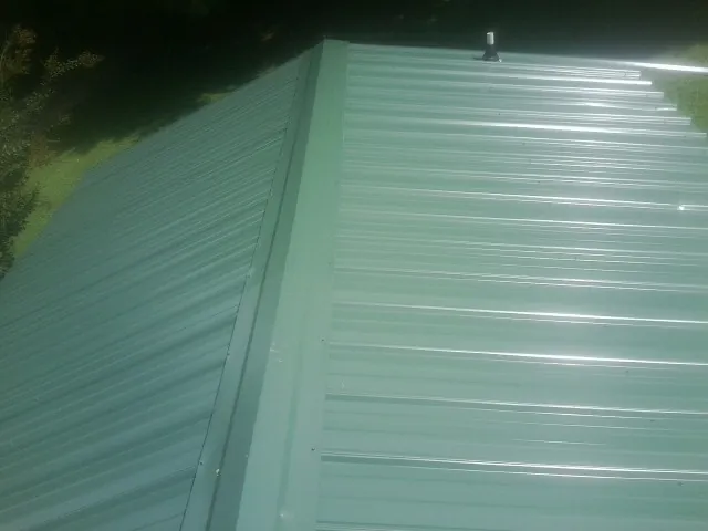 New green metal panels meeting at the ridge of a roof — Flat Roof Repair work by our crew in New Buffalo