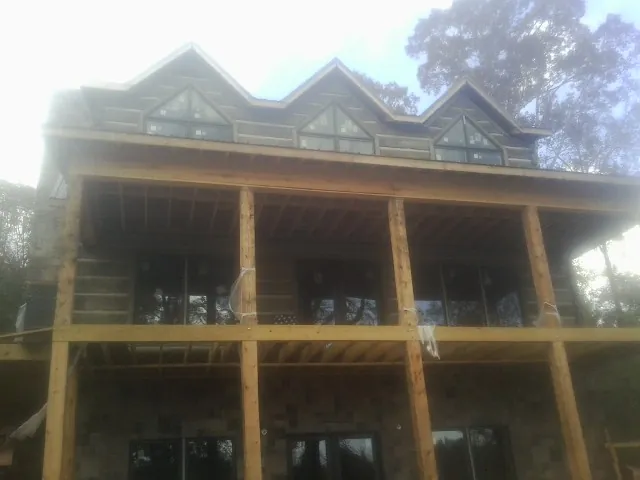 Dormers and porch framing on a large log home under construction — Roof Coating work by our crew in New Buffalo