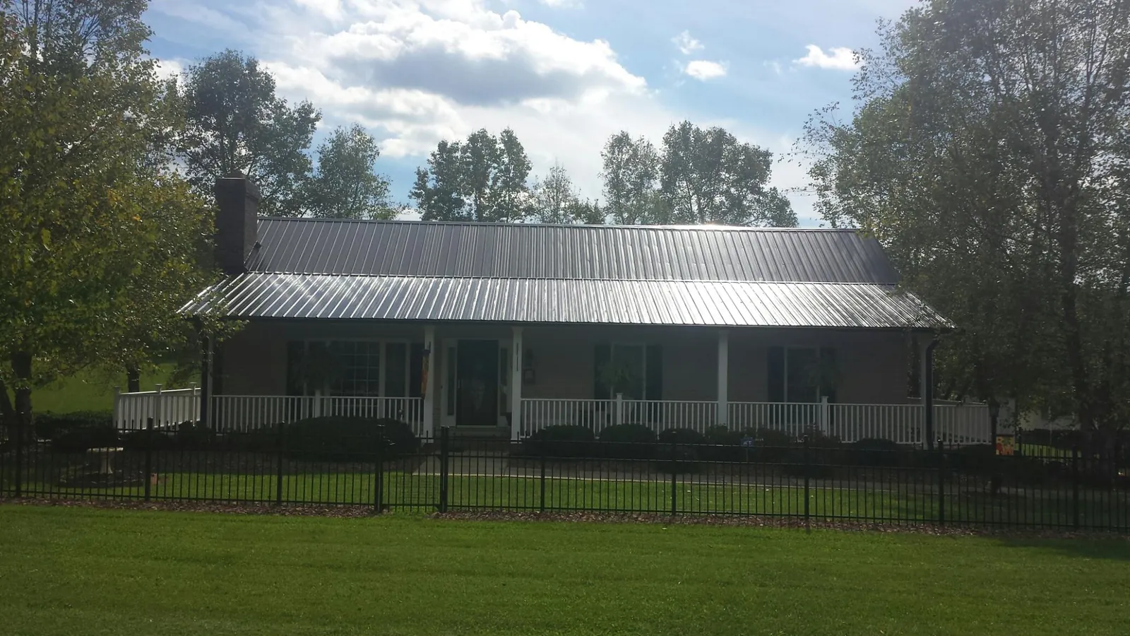 Gray metal roof on a brick ranch with a full width front porch — Gutter Guard Installation work by our crew in New Buffalo
