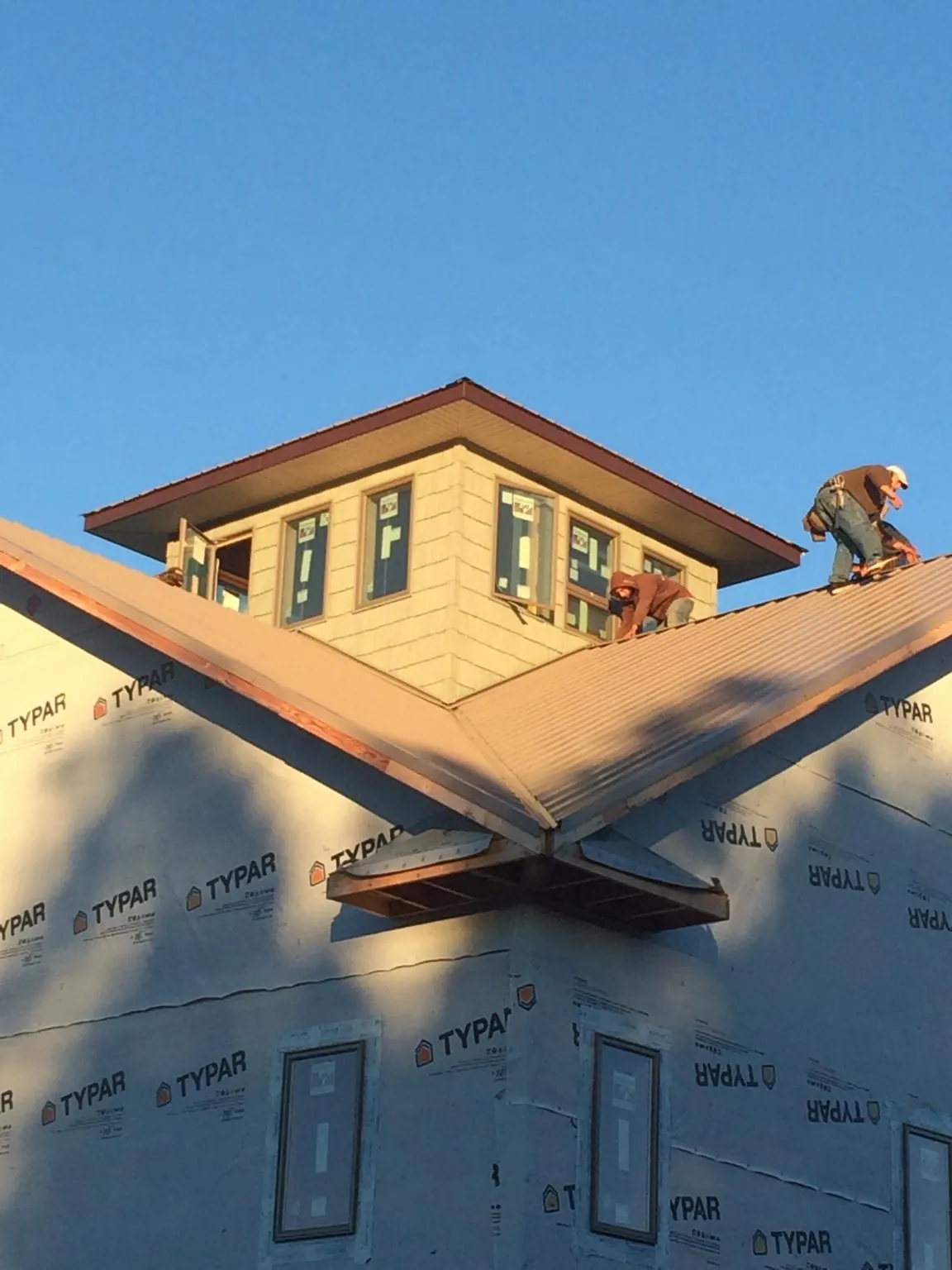Roofers working around a rooftop cupola on a new metal roof at sunset — Roof Waterproofing in New Buffalo by Roofing Brothers